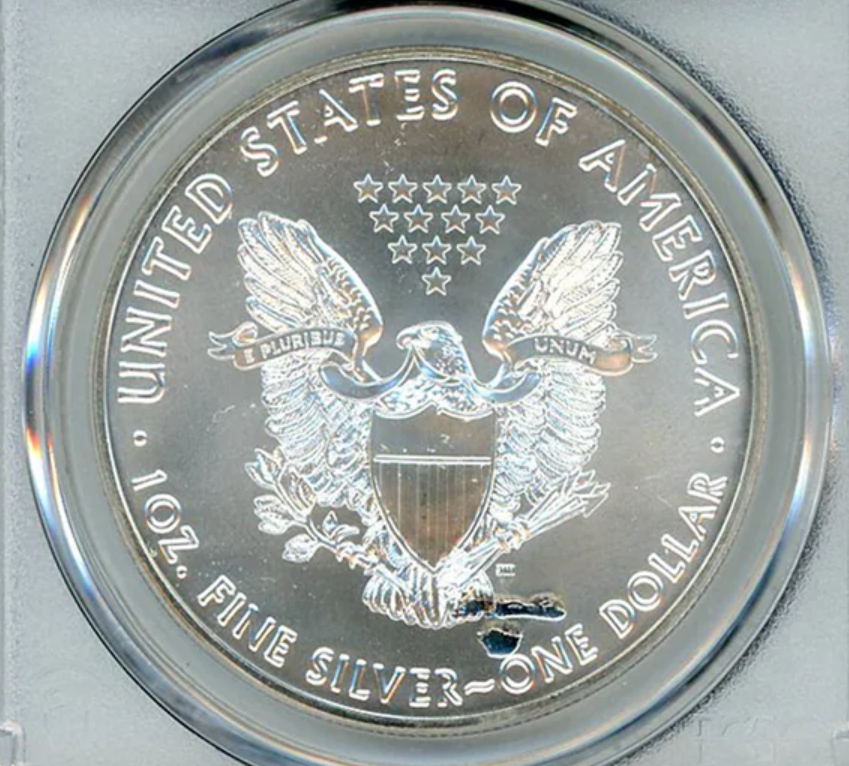 Close-up of a 2016 American Silver Eagle showing struck-through error where debris prevented full design impression during striking